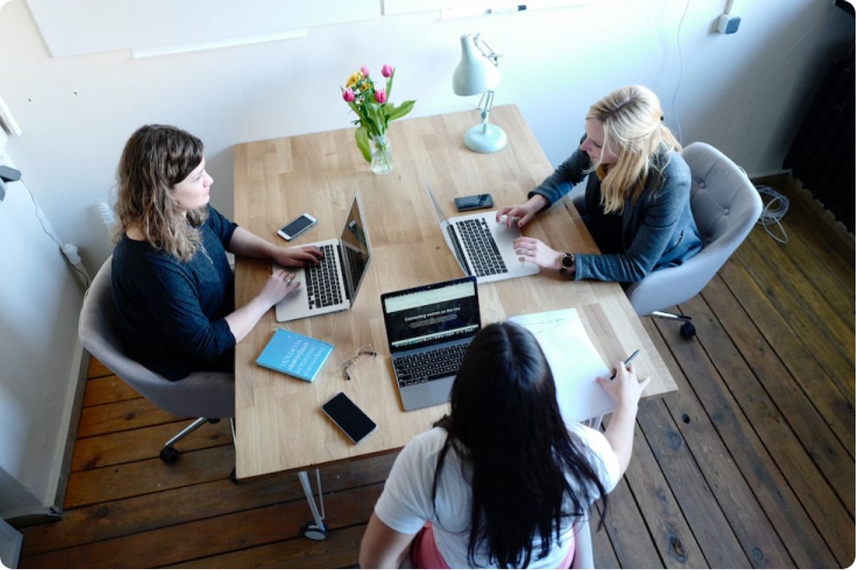 Woman sitting around a desk with laptops