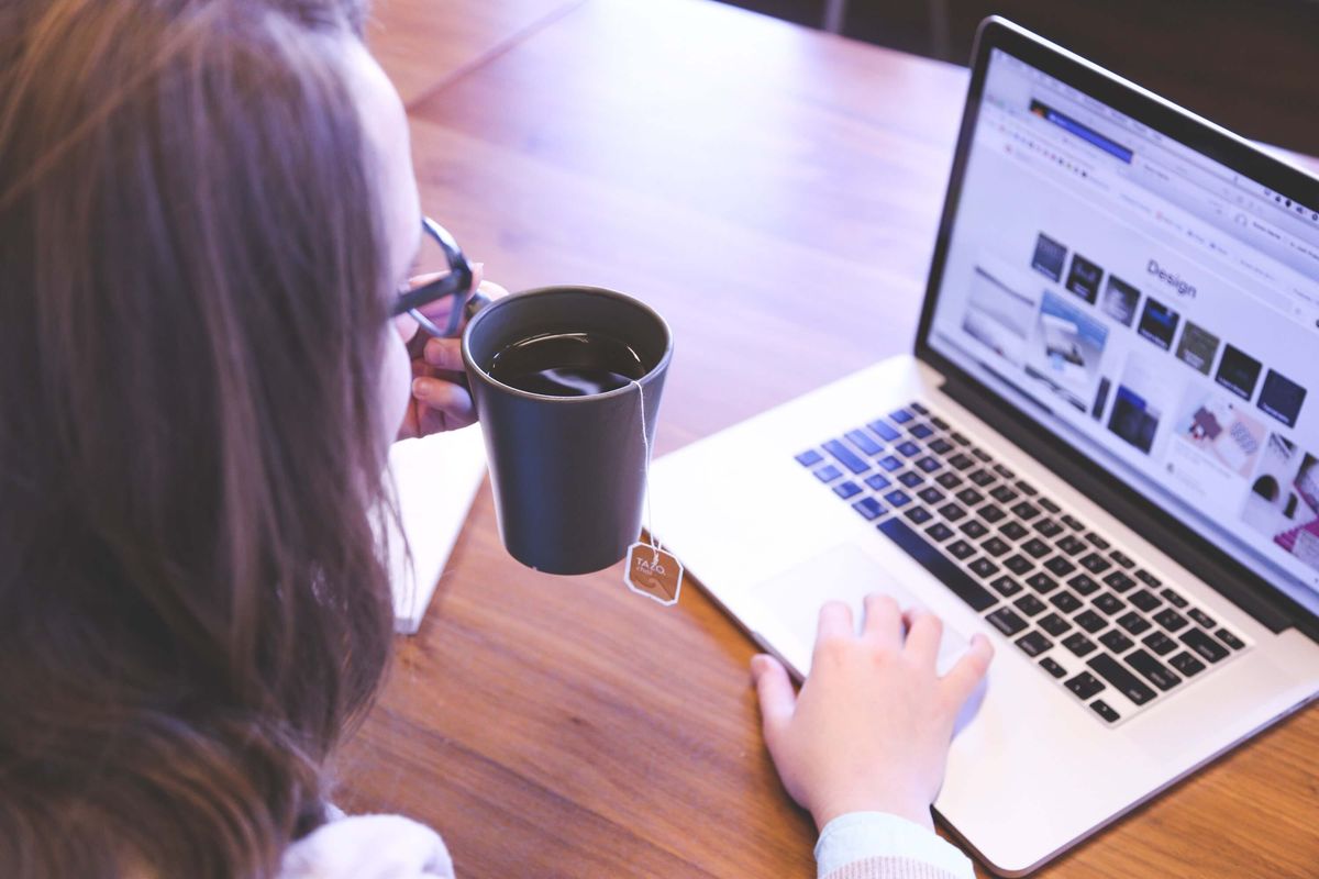 Woman checking her email with tea in her hand